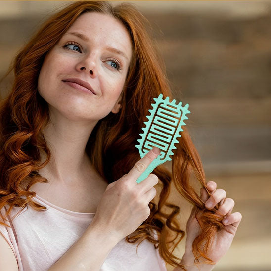 femme heureuse brossant cheveux avec brosse a cheveux demelante